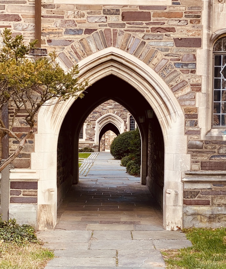 A run of pointed stone arches over a flagstone path