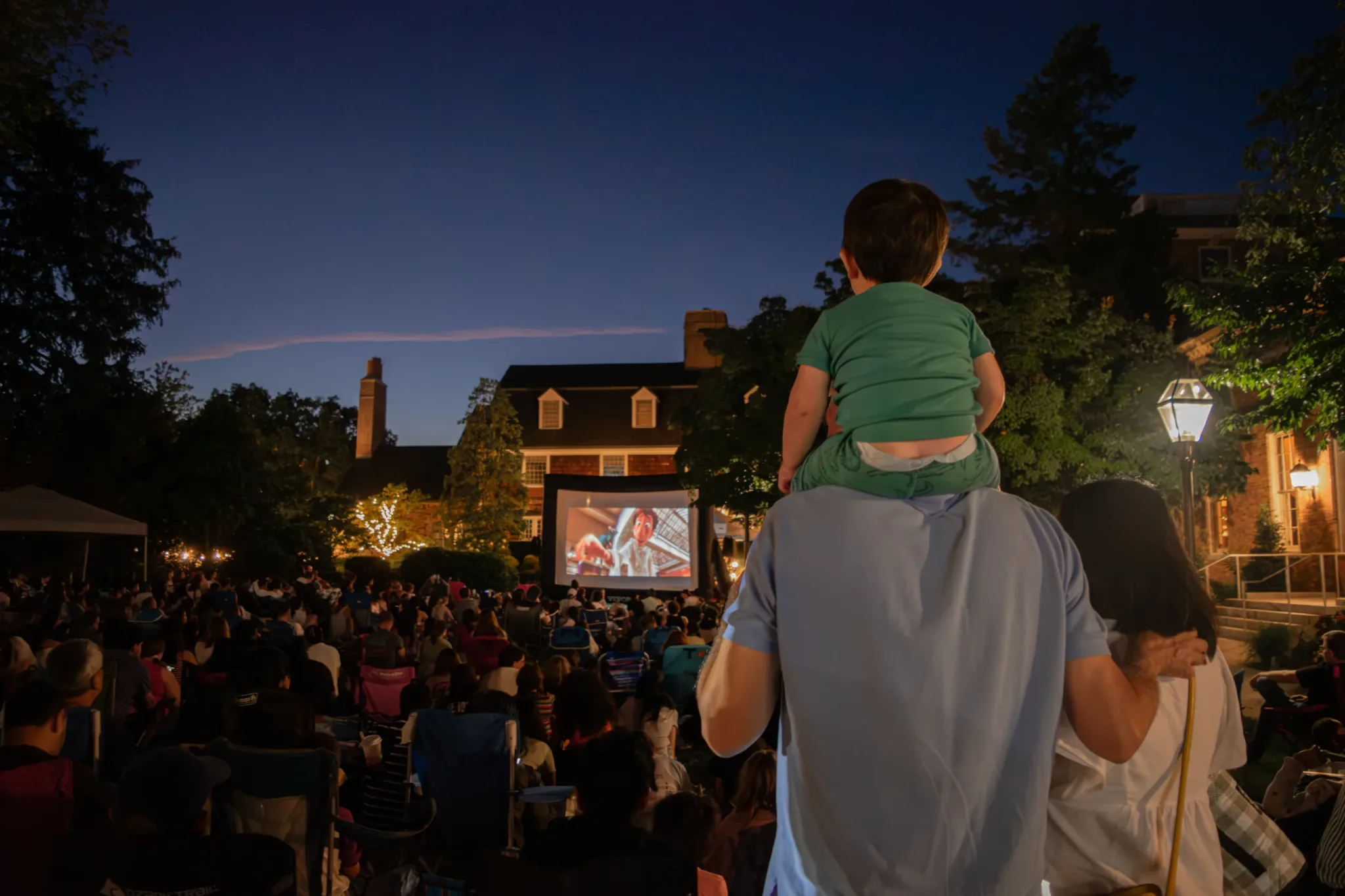 Families watching an outdoor film screening at dusk
