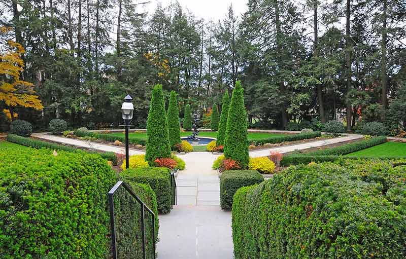 A formal garden in full leaf with clipped hedges
